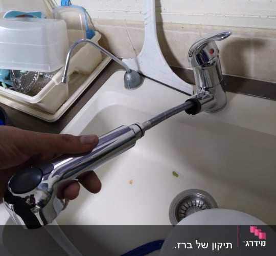 ברז מטבח עם צינור נשלף ביד אדם